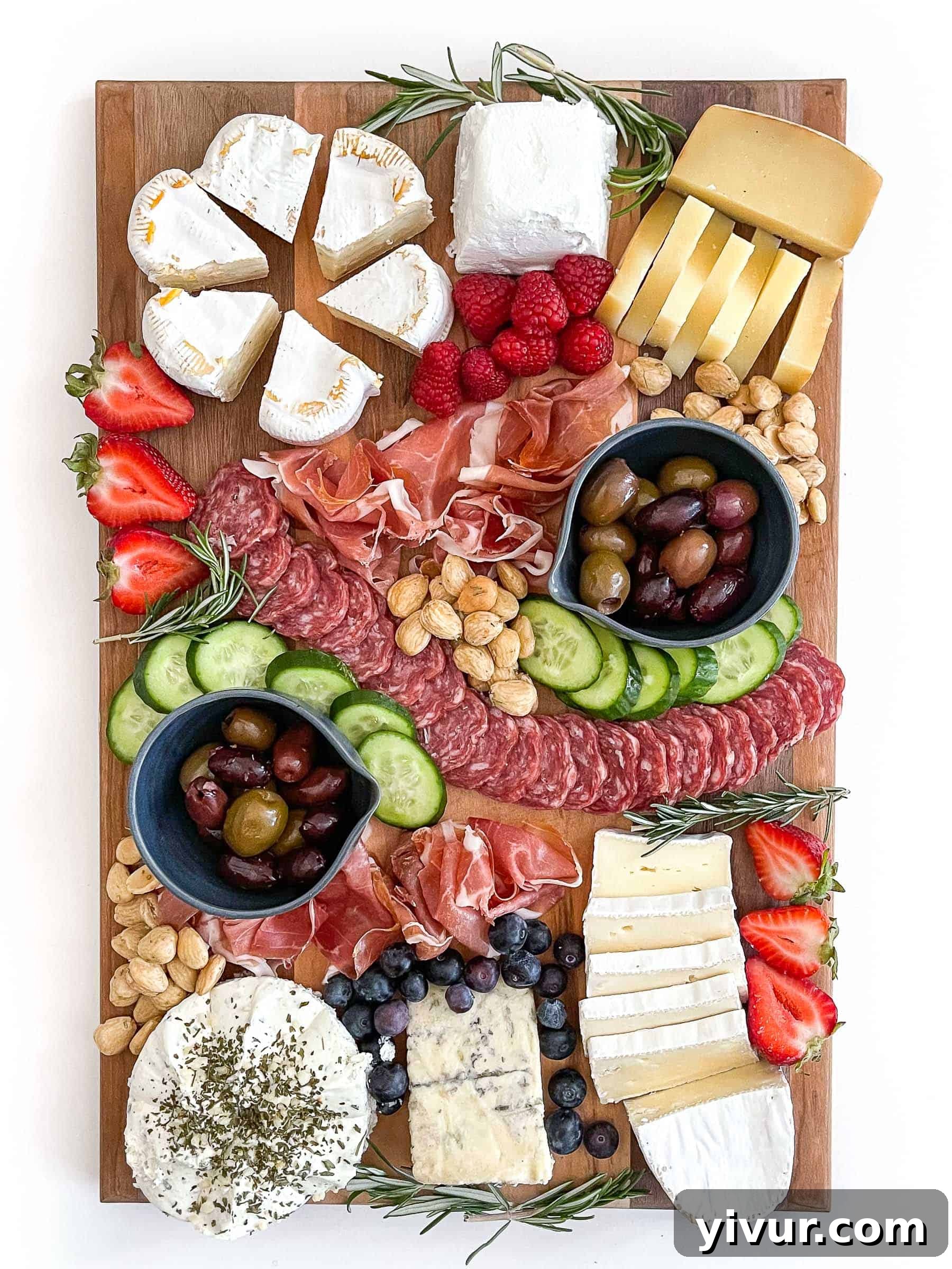 Sunshine Keto Cheese Platter 2 Keto friendly cheese board with sliced cheese, salami, cucumber, nuts, olives and berries, garnished with fresh rosemary