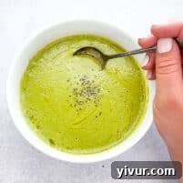 A bowl of creamy green asparagus soup, garnished with a drizzle of olive oil, ready to be enjoyed.