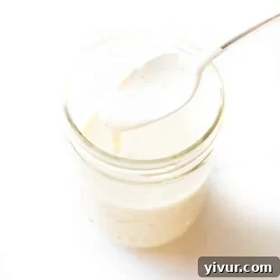 Spoon pouring a white sauce into a mason jar