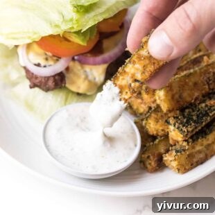 Hand dipping keto zucchini fries in ranch dressing