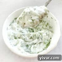 Keto Tzatziki Sauce in a white bowl with a spoon