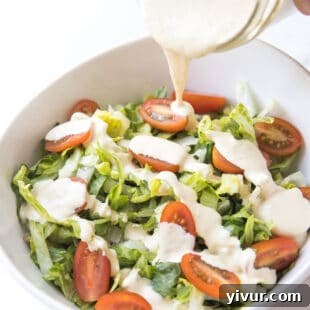 Pouring keto caesar dressing over salad
