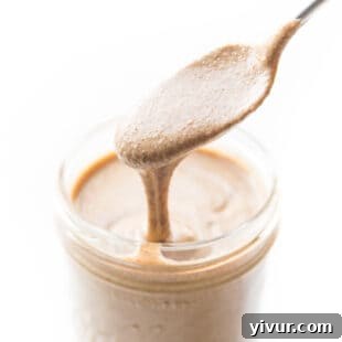 Spoon pouring mixed nut butter into a mason jar