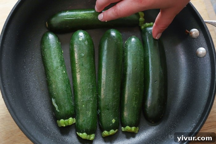 Zucchini halves searing face down in a pan
