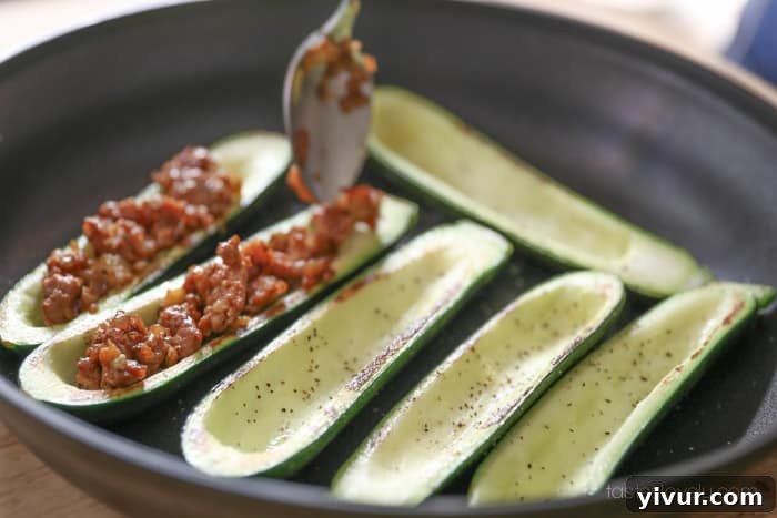 Stuffing zucchini with sausage mixture