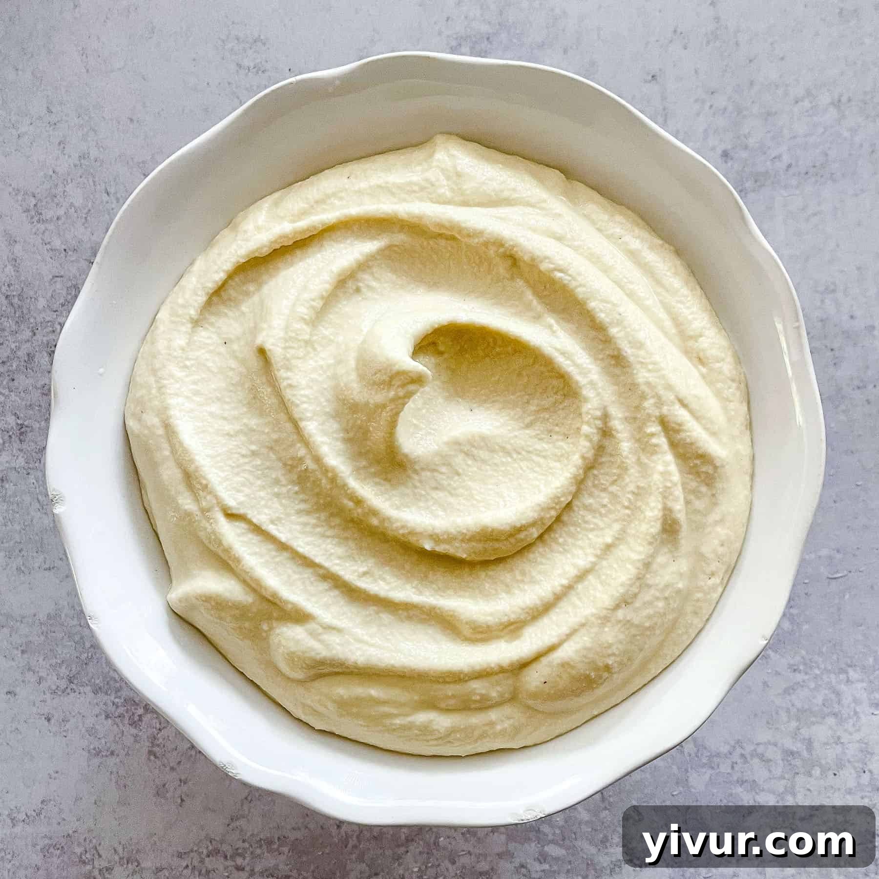 Freshly made dairy-free ricotta in a white bowl, garnished and ready to be served.