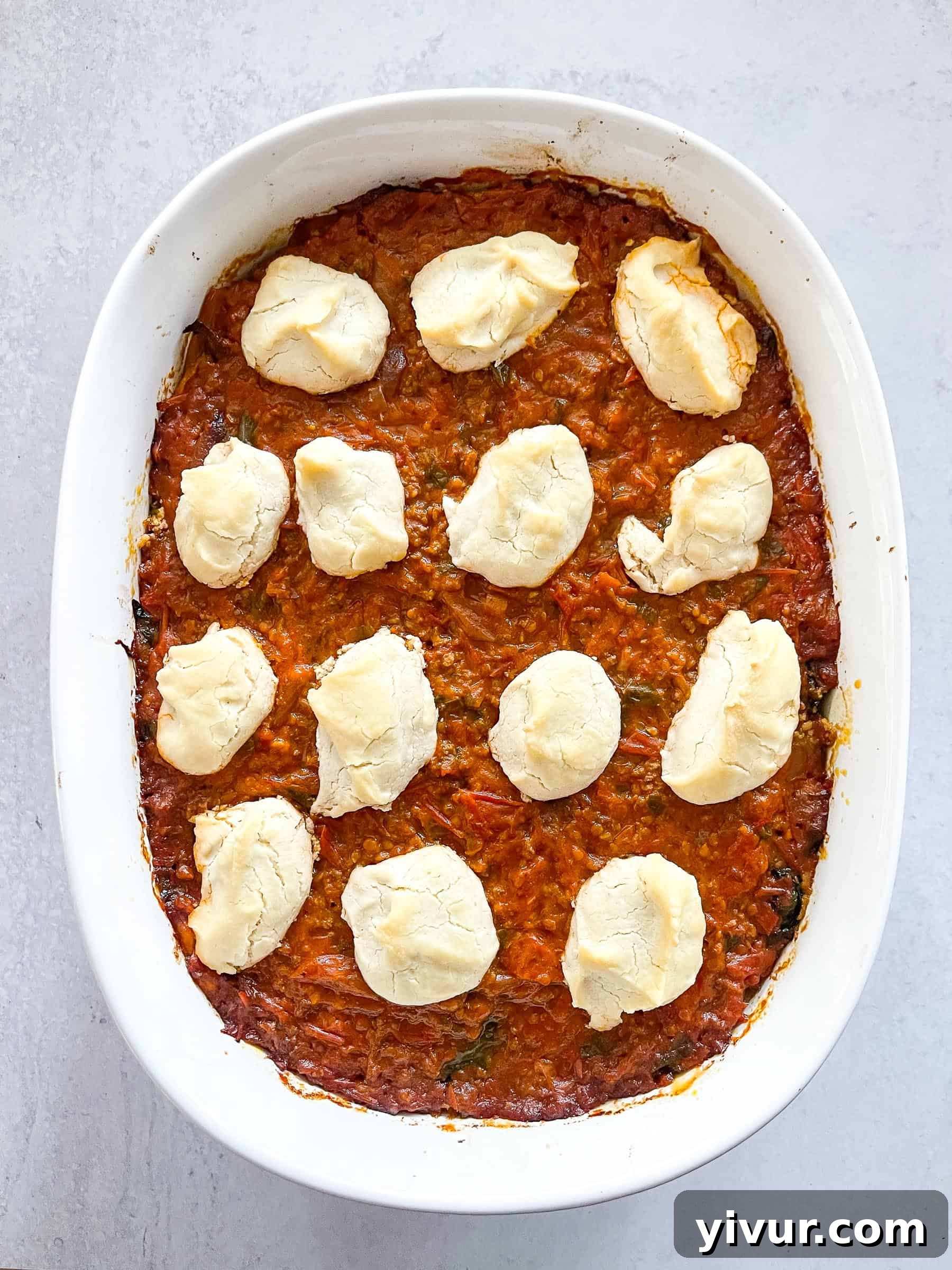 A glorious dairy-free keto lasagna in a white baking dish, fresh out of the oven, topped with dollops of creamy dairy-free ricotta cheese.