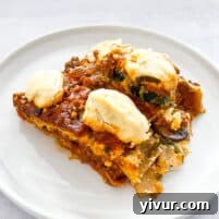 Dairy free lasagna topped with dairy free ricotta cheese on a white plate with a white background