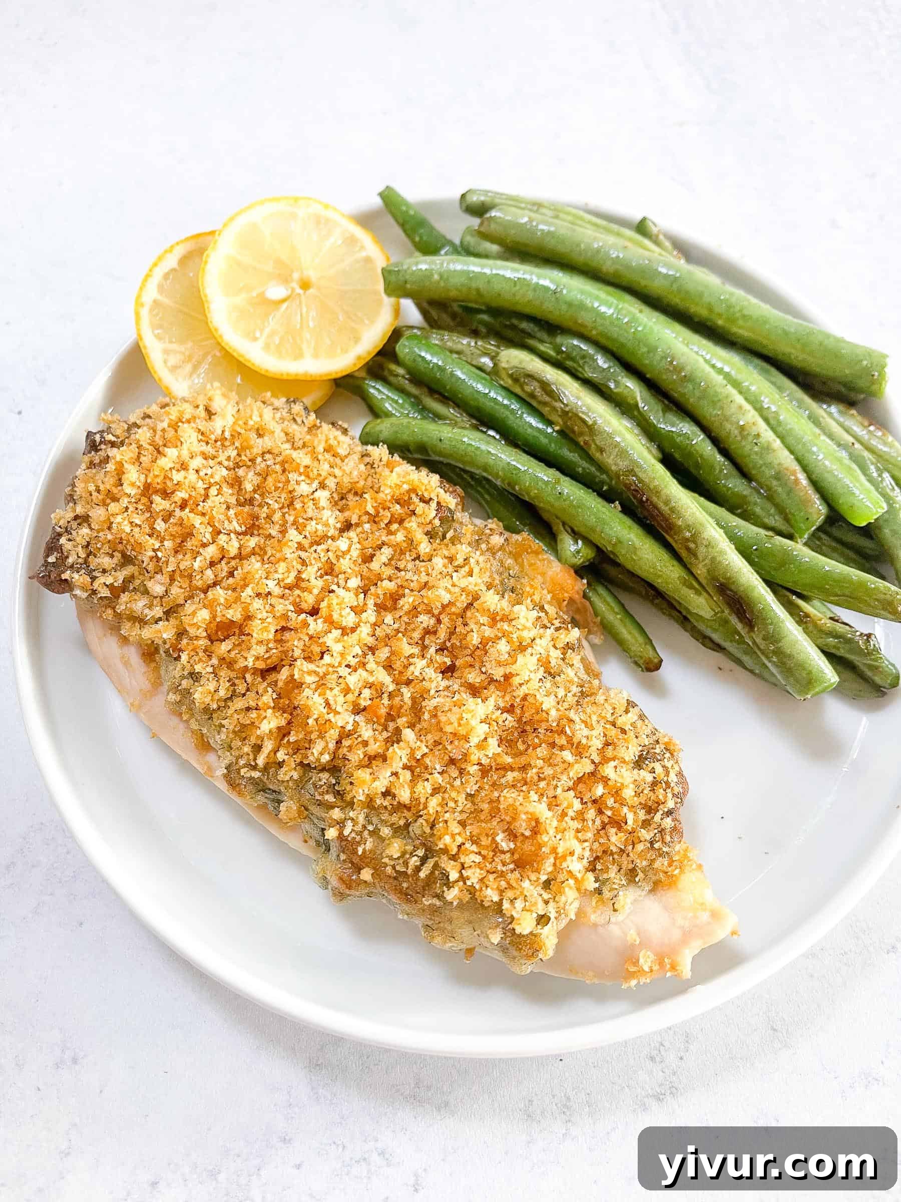 Keto Crispy Ranch Chicken with vibrant green beans and a lemon wedge, artfully arranged on a pristine white plate, set against a clean white background.