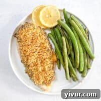 keto crispy ranch chicken with green beans and lemon garnish on a white plate with a white background