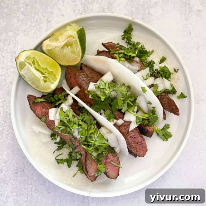 steak tacos on jicama wrap on a white plate with lime and a white background