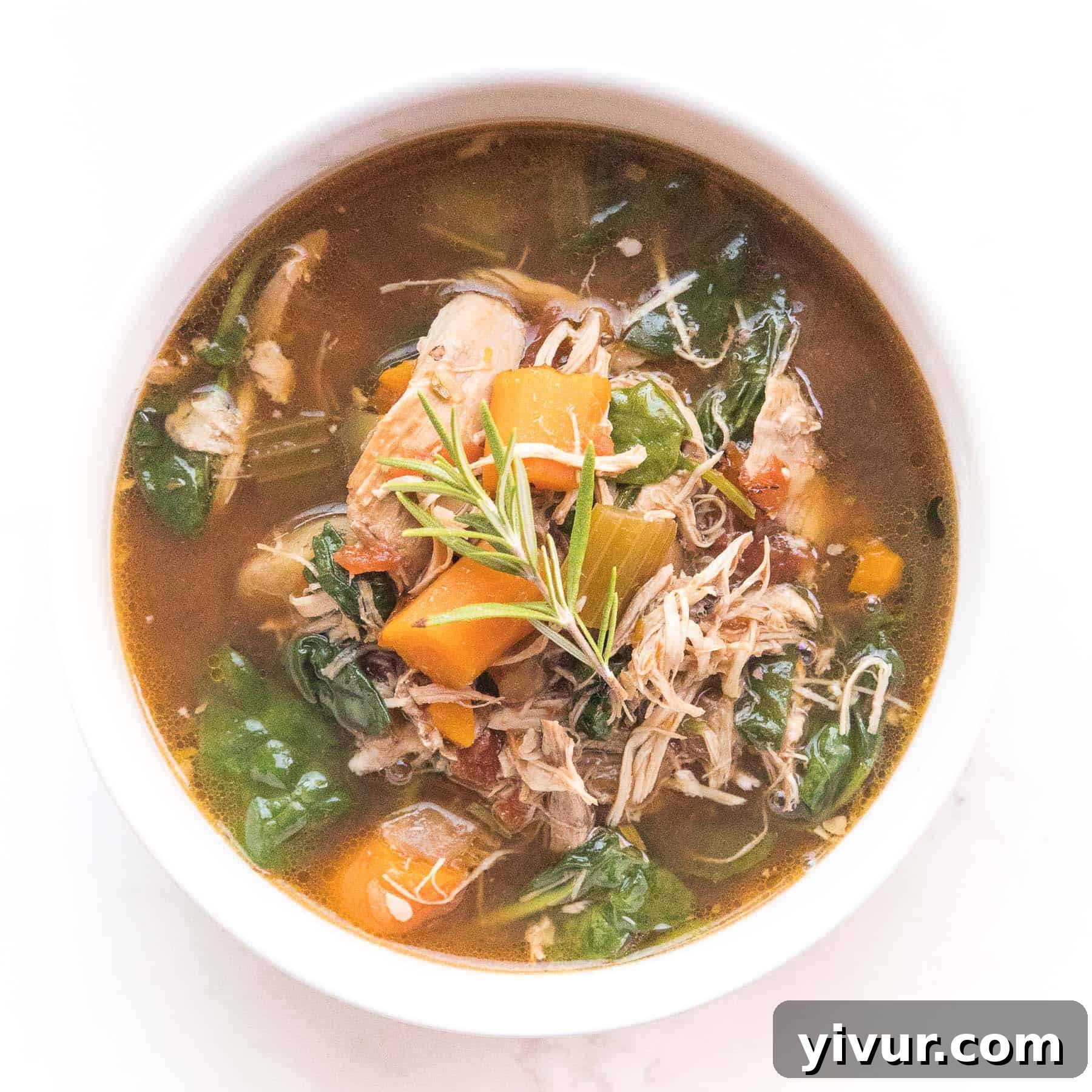 Hearty Keto Tuscan chicken soup with spinach and creamy broth, served in a bowl.