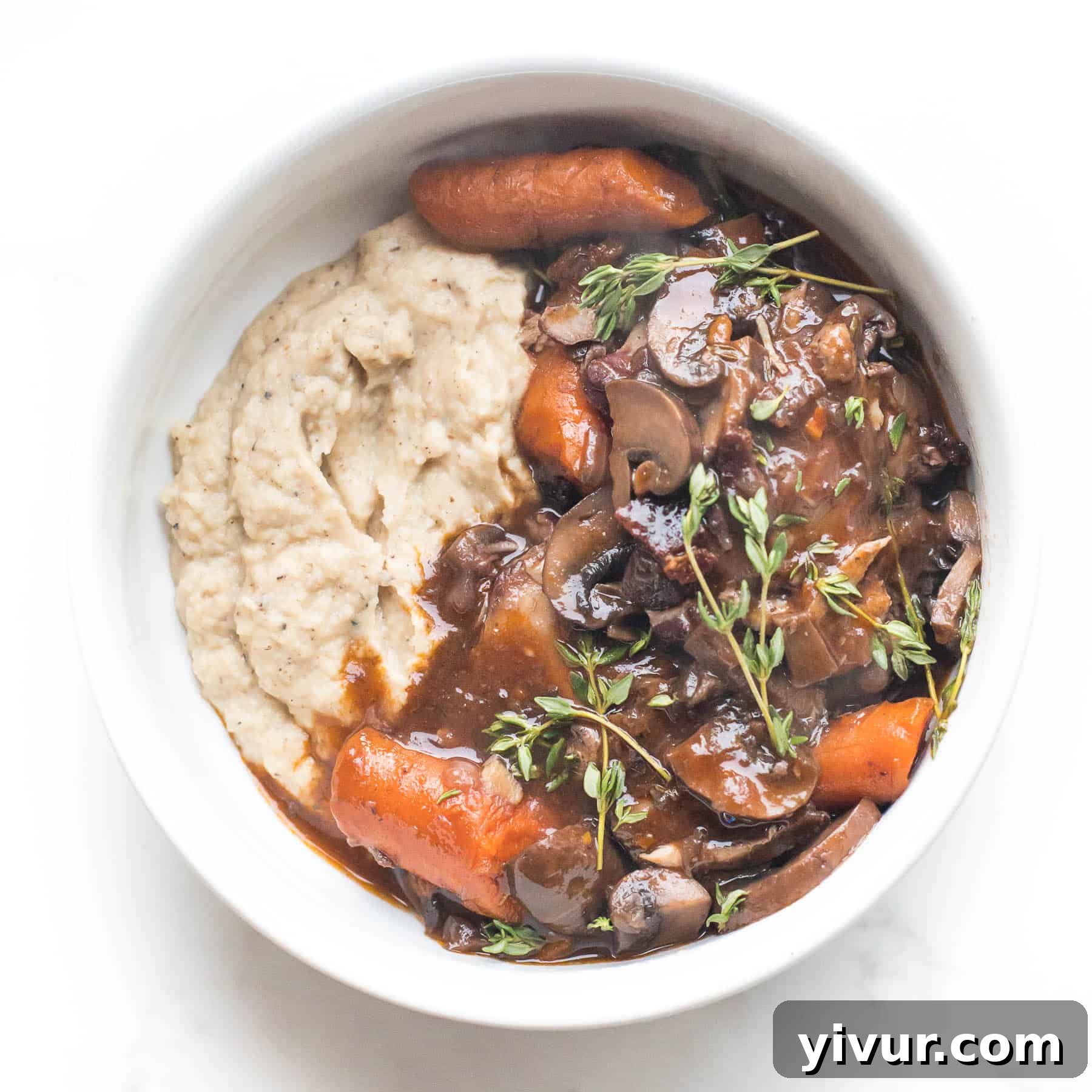 Keto Instant Pot Coq Au Vin with mashed cauliflower in a white bowl on a white background.