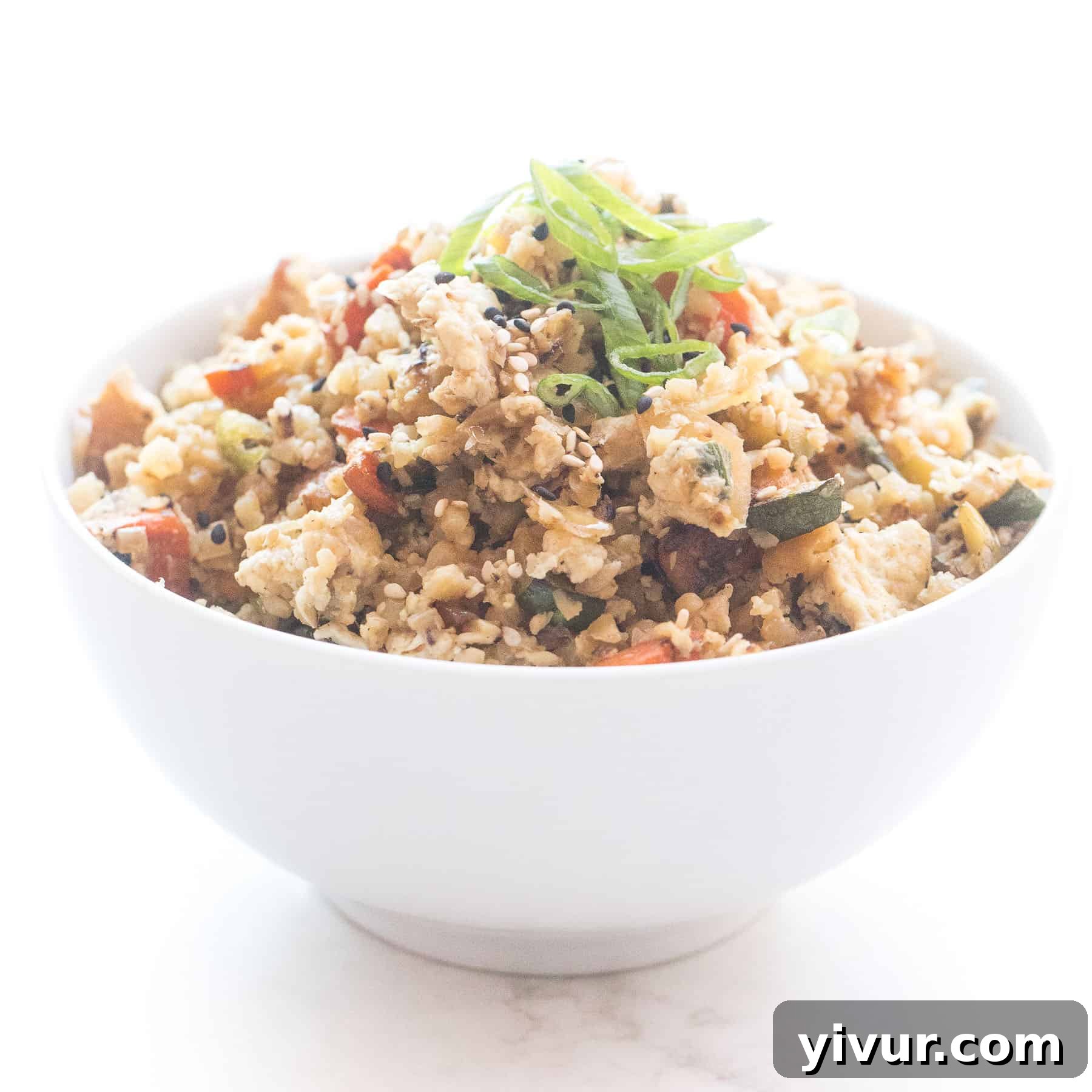 Whole30 + Keto cauliflower fried rice in a white bowl, a healthy and low-carb alternative to traditional fried rice.