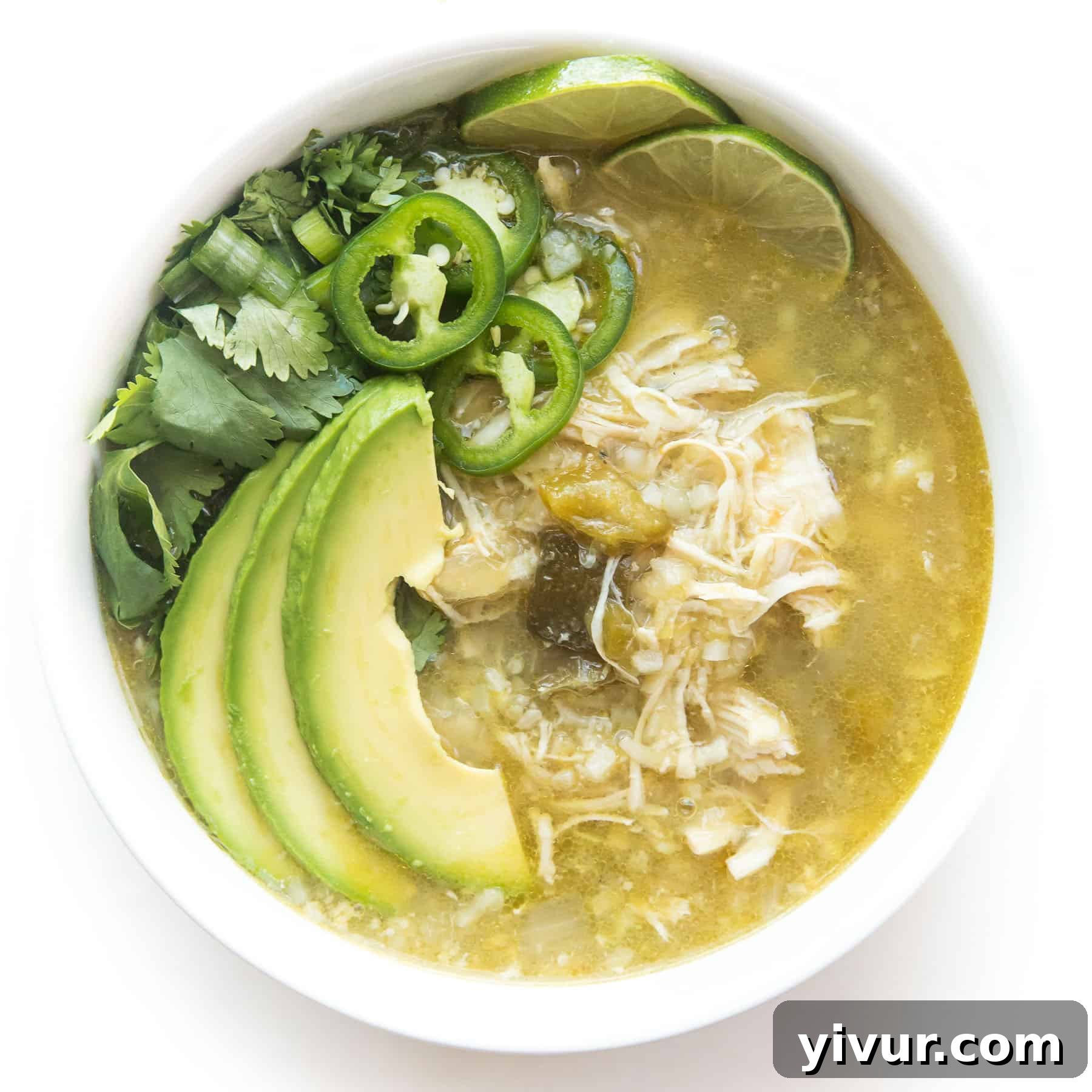 Hearty verde chicken chili in a white bowl on a white background, cooked quickly in an Instant Pot for a keto and Whole30 meal.