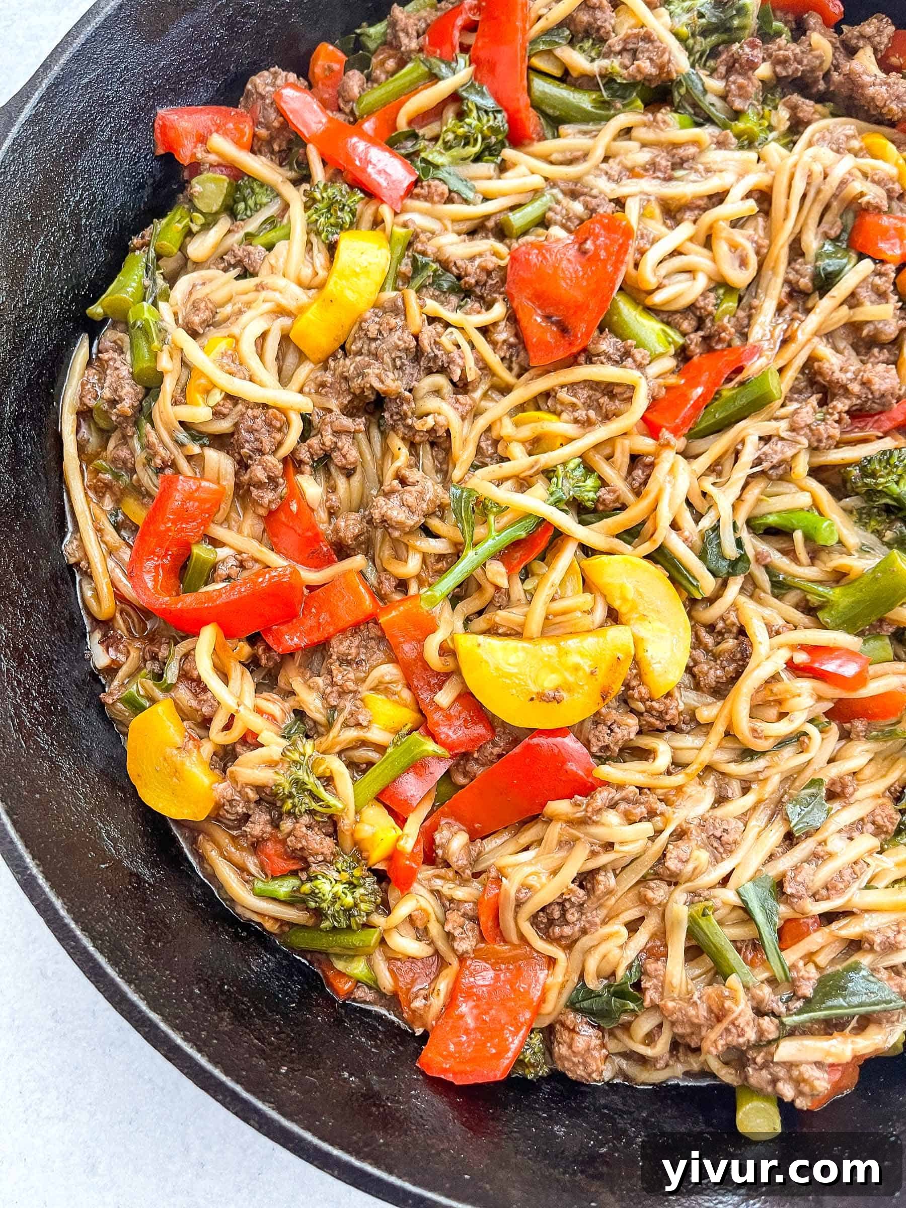 Overhead view of keto beef and vegetable noodle stir fry cooking in a cast iron skillet