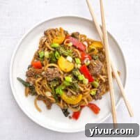 keto beef and vegetable noodle stir fry on a white plate with two chopsticks and a white background
