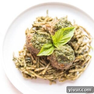 Pesto meatballs served over a bed of green pesto hearts of palm low-carb noodles.