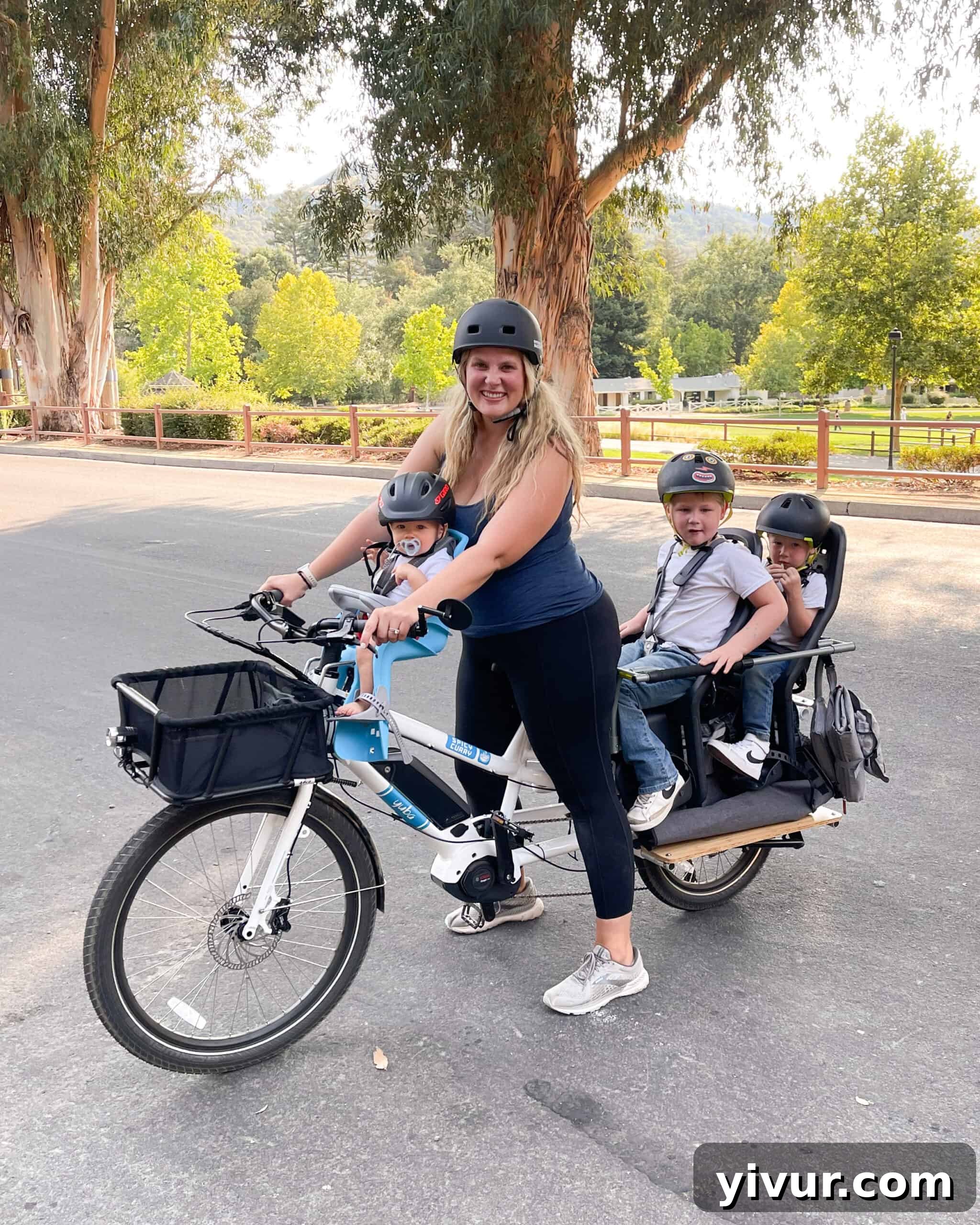 A mom joyfully riding her electric family cargo bike with three kids in tow, showcasing daily family adventures.