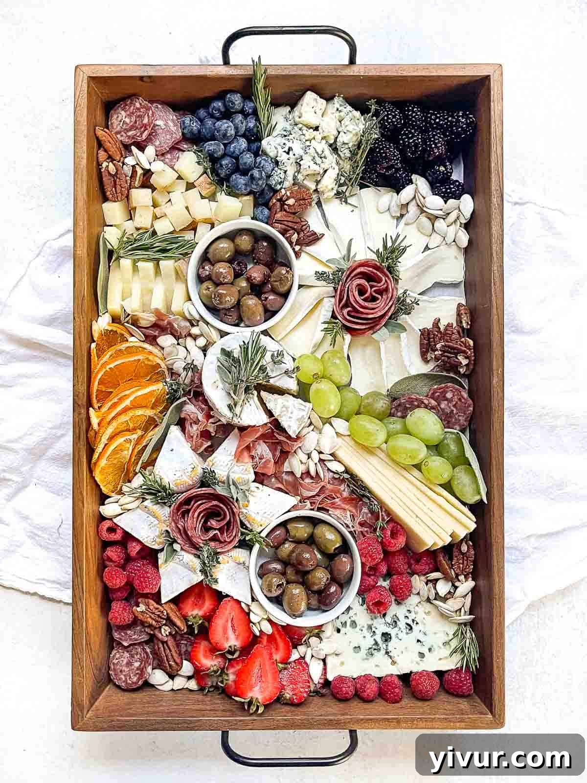 overhead shot of a styled Christmas charcuterie board with cheeses, meats, fruit and nuts, adorned with festive touches