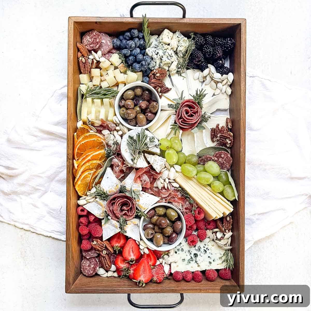 an overhead shot of a meticulously styled cheese board filled with an abundant variety of meats, cheeses, fruits, and nuts.