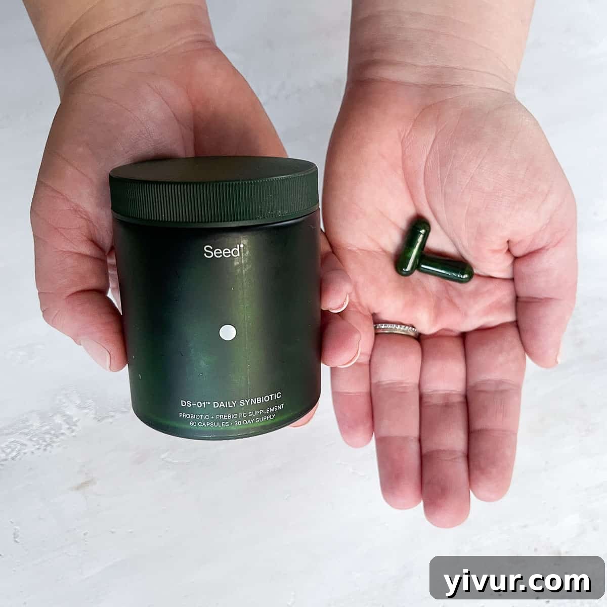 Seed Probiotics: My Year-Long Gut Health Transformation 3 Hands holding a bottle of Seed probiotics and two Seed capsules, emphasizing the product's tangible presence and ease of use.