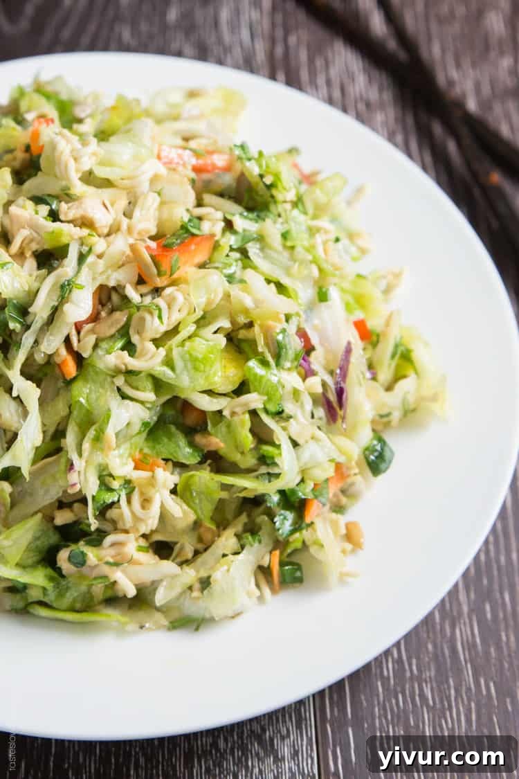 A vibrant and healthy Ramen Noodle Chinese Chicken Salad in a bowl, showcasing shredded cabbage, bell peppers, green onions, and golden ramen noodles.