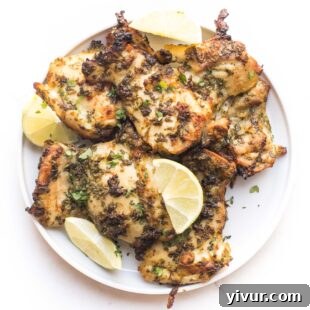 Whole30 and Keto Cilantro Lime Chicken Thighs on a white plate, garnished with fresh cilantro and lime wedges.