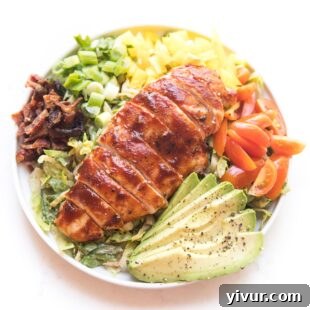 Make Dad's Day Delicious: Keto Recipes and Gift Ideas for Fathers Day 2022 14 bbq chicken salad with avocado, bacon, bell pepper, tomatoes and green onions on a white plate and background