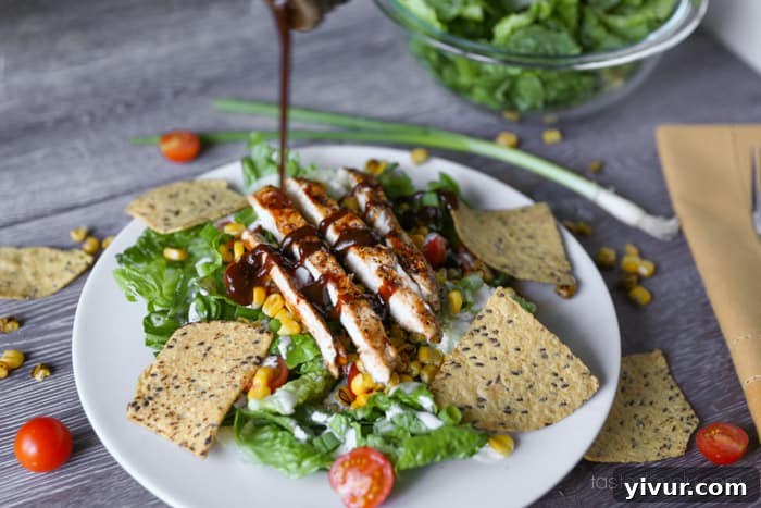Finishing touch: Drizzling extra BBQ sauce over the grilled chicken on the prepared salad