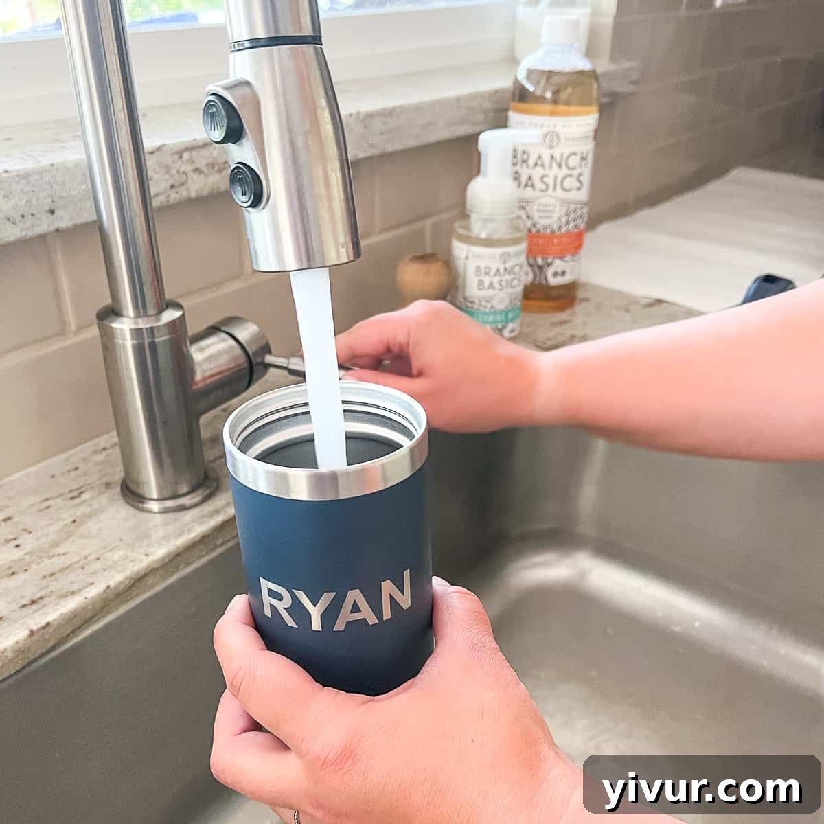Cleaned reusable water bottle getting filled with water at a kitchen sink, emphasizing freshness and hygiene.