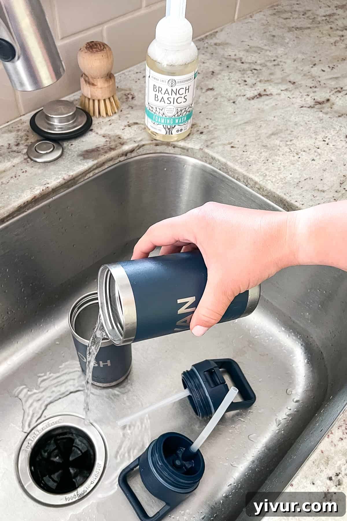 Pouring out residual water from a reusable water bottle into the sink, the first step in the cleaning process.
