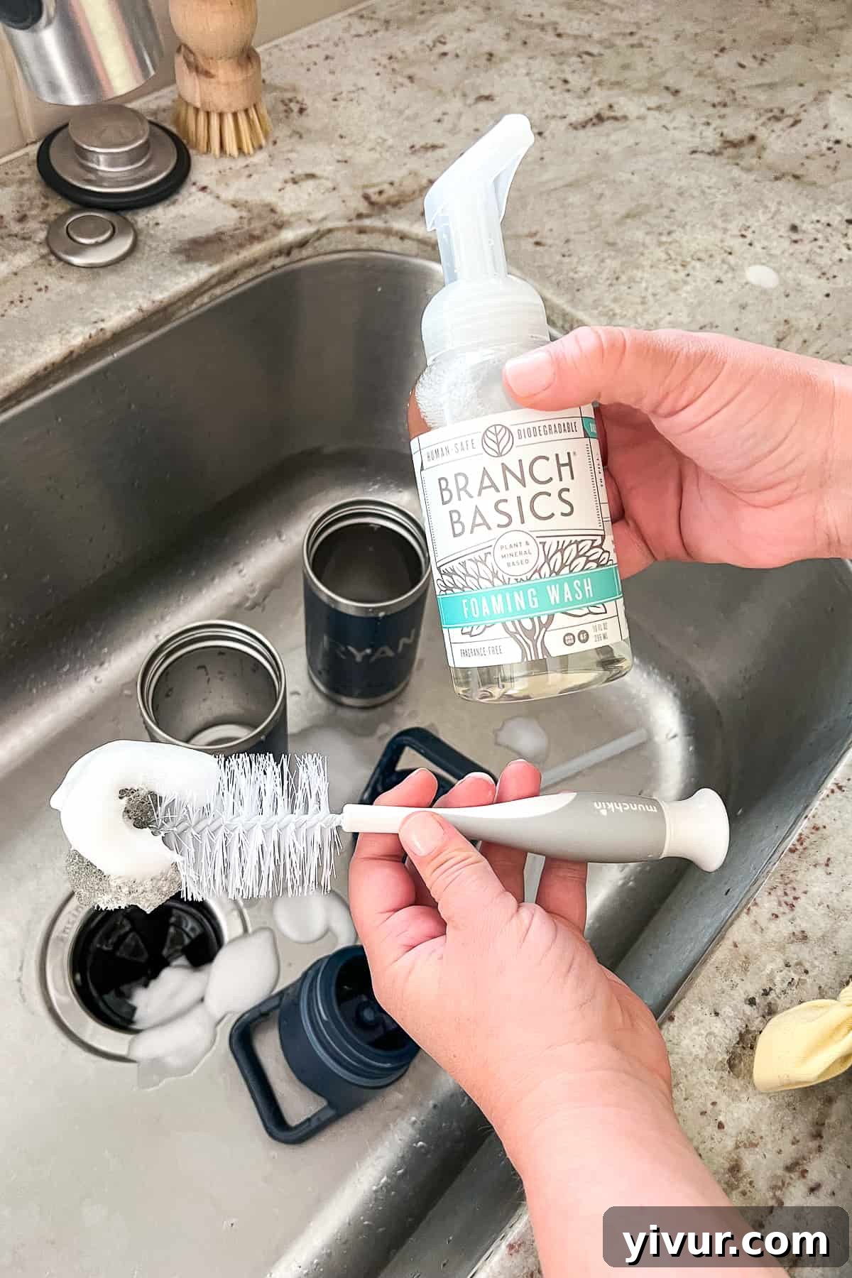 Applying Branch Basics foaming soap directly onto a bottle brush, preparing it for scrubbing the interior of the water bottle.