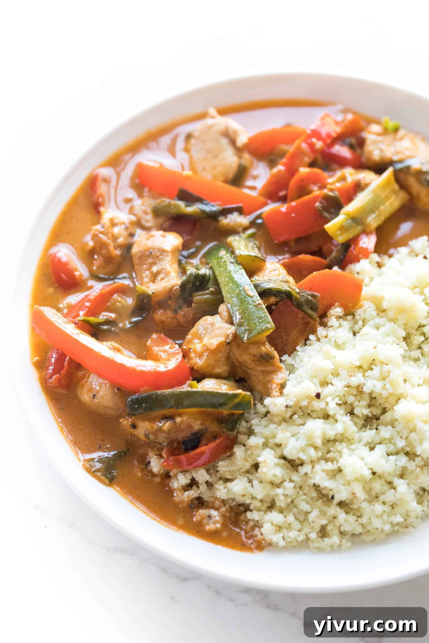 30-Minute Keto Thai Coconut Chicken Curry 2 Thai keto chicken curry with vegetables served over cauliflower rice on a white plate.