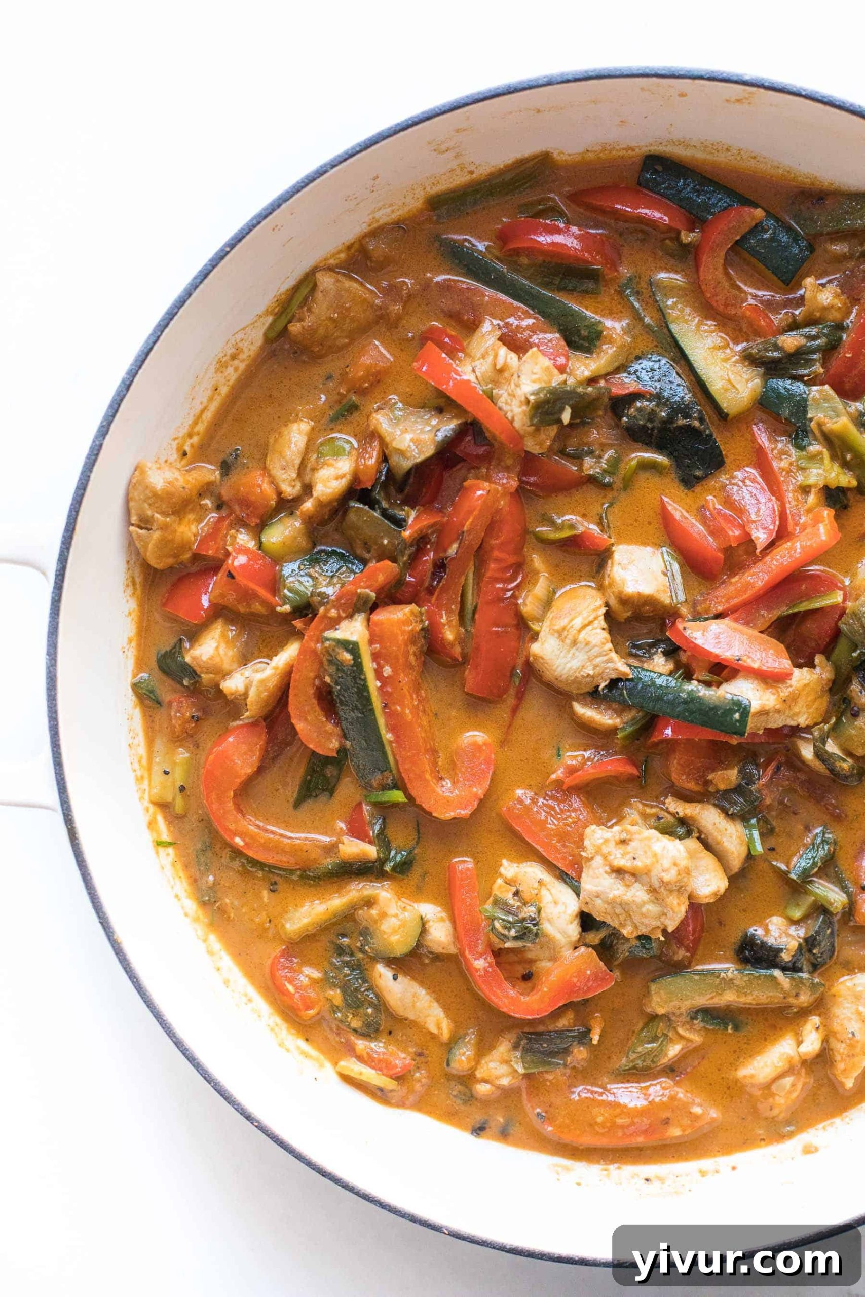 30-Minute Keto Thai Coconut Chicken Curry 4 Keto chicken curry simmering in a white skillet, showcasing tender chicken and vegetables.