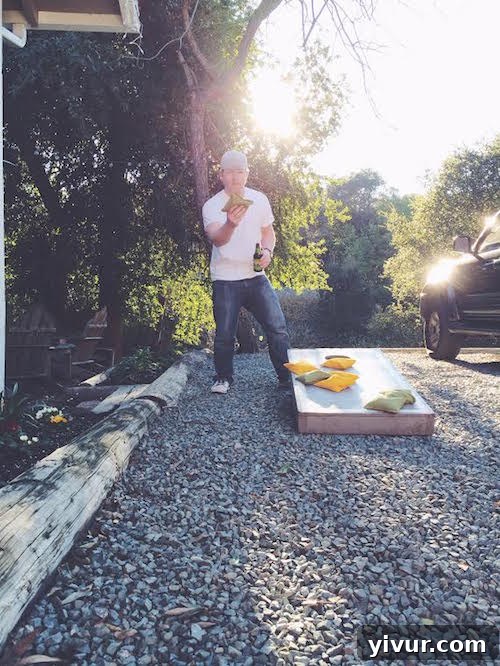 Friends playing cornhole in a sunny backyard with drinks