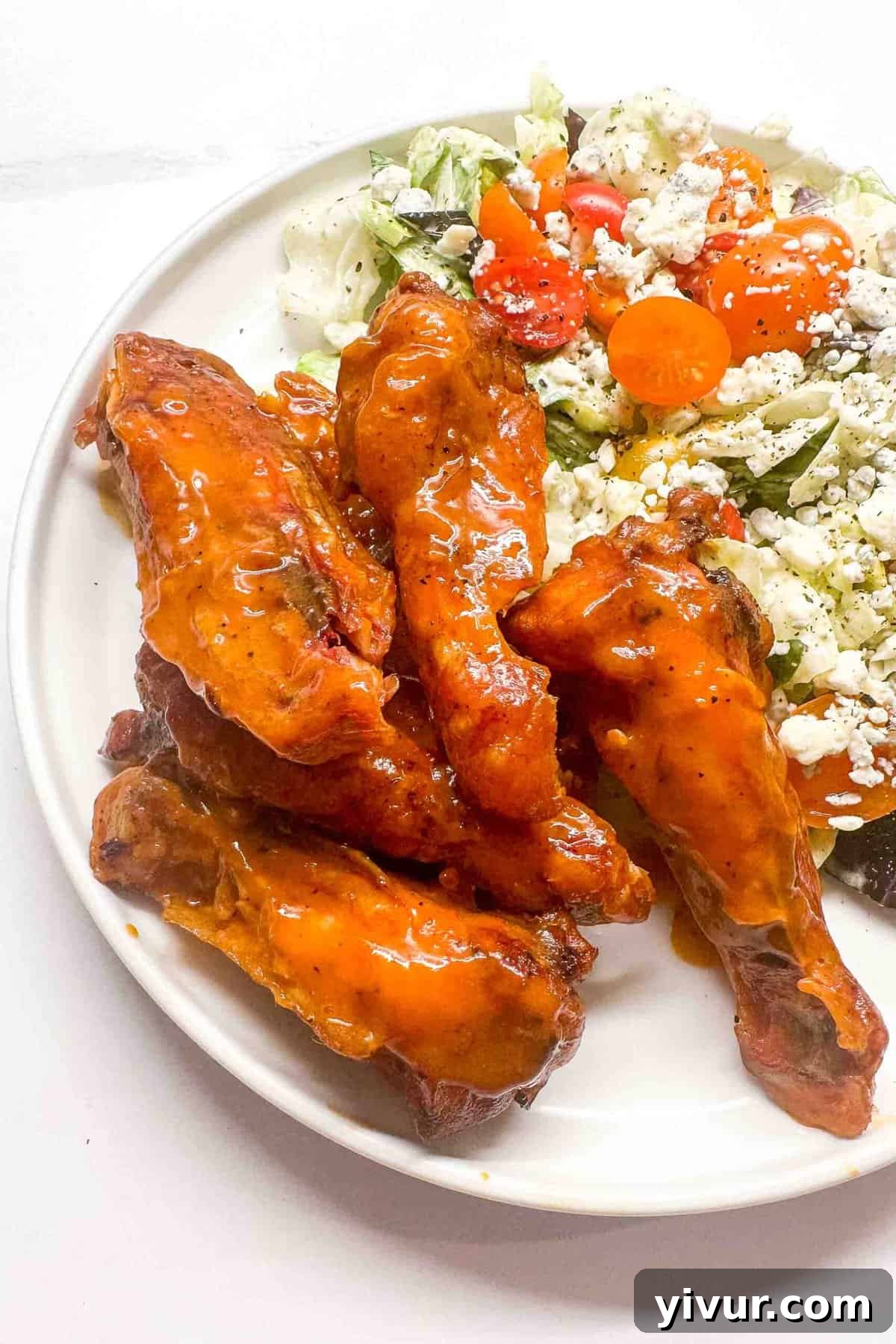 a close up of smoked buffalo wings on a plate with a side salad