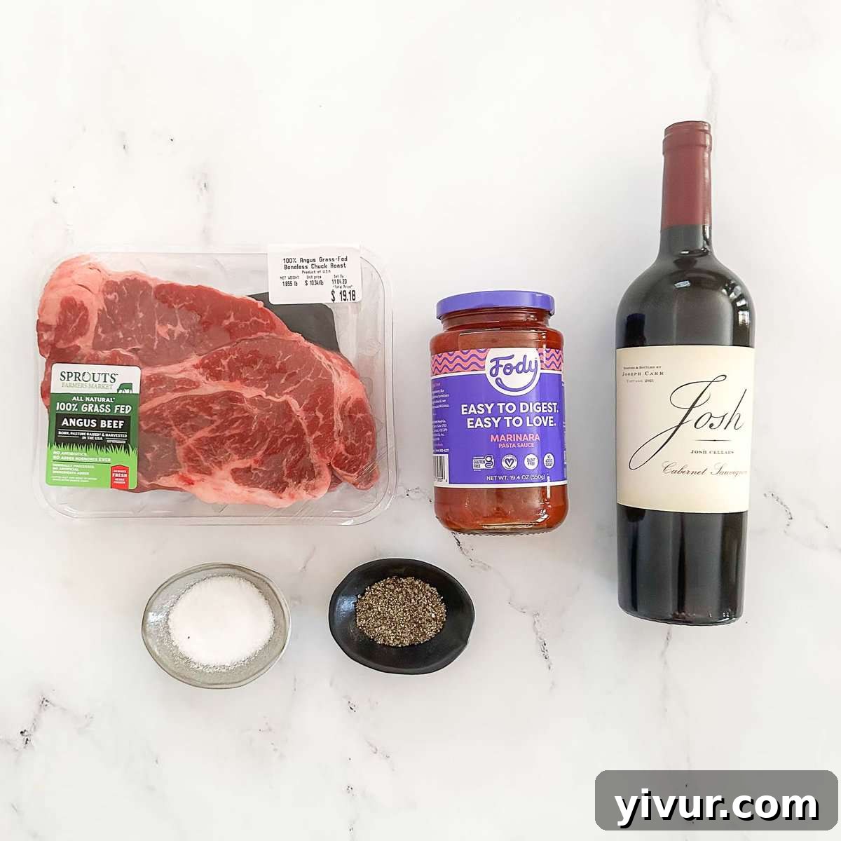 Effortless Instant Pot Beef Ragu 4 A selection of raw ingredients for Instant Pot Beef Ragu: chuck roast, marinara sauce jars, and a bottle of red wine on a white surface.