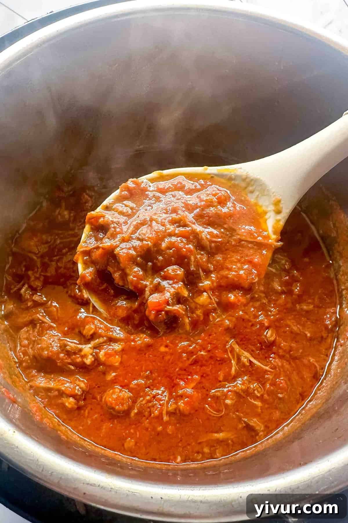 Effortless Instant Pot Beef Ragu 6 A wooden spoon scooping rich, shredded beef ragu out of an Instant Pot, showing the tender consistency of the meat.