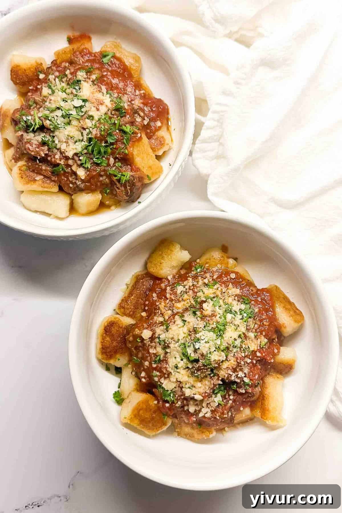 Effortless Instant Pot Beef Ragu 7 An overhead shot showcasing two inviting bowls of Instant Pot Beef Ragu served over cauliflower gnocchi, garnished with fresh parsley and Parmesan.