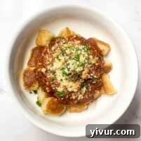 Effortless Instant Pot Beef Ragu 8 Instant pot beef ragu in a white bowl, garnished with herbs.