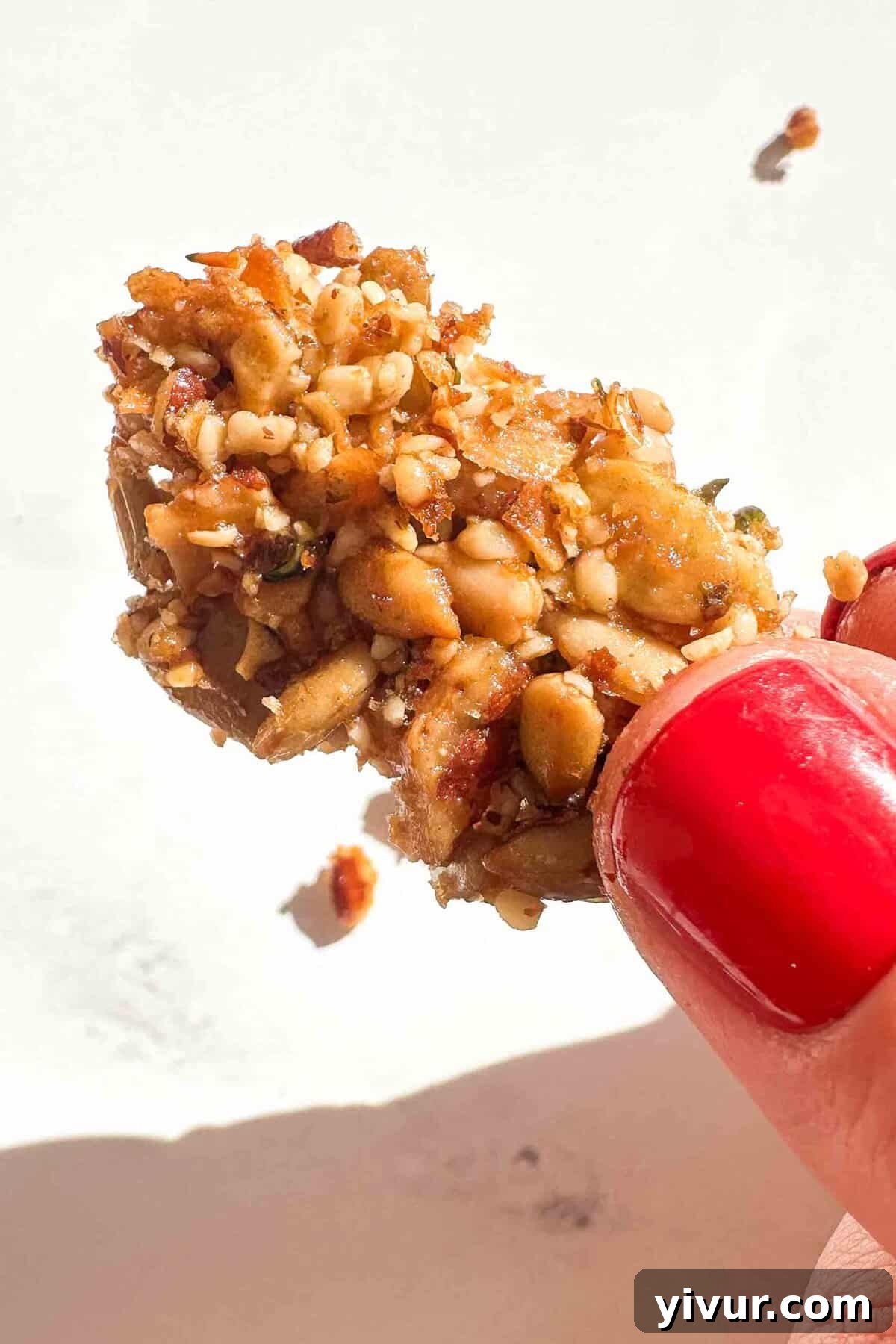 a hand holding a tiny piece of nut clusters 