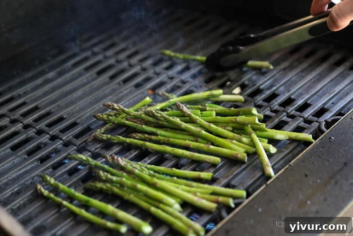 Perfect Grilled Asparagus 11 Asparagus spears being tossed on the grill for even cooking