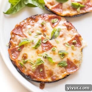 keto mini cauliflower thin pepperoni pizzas on a white plate topped with fresh basil