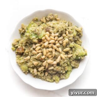 pesto cauliflower rice, broccoli, meatballs and pinenuts in a white bowl