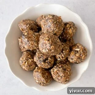 A plate of perfectly formed no-bake keto energy balls, some coated in shredded coconut, others with chocolate drizzle.