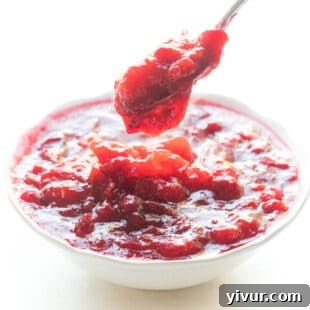 Spoon dripping cranberry sauce in a white bowl