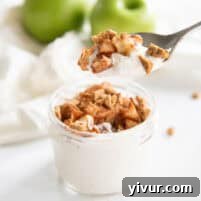 A scoop of high-protein apple pie cheesecake topped with baked apples and graham cracker crumbs in a mason jar.