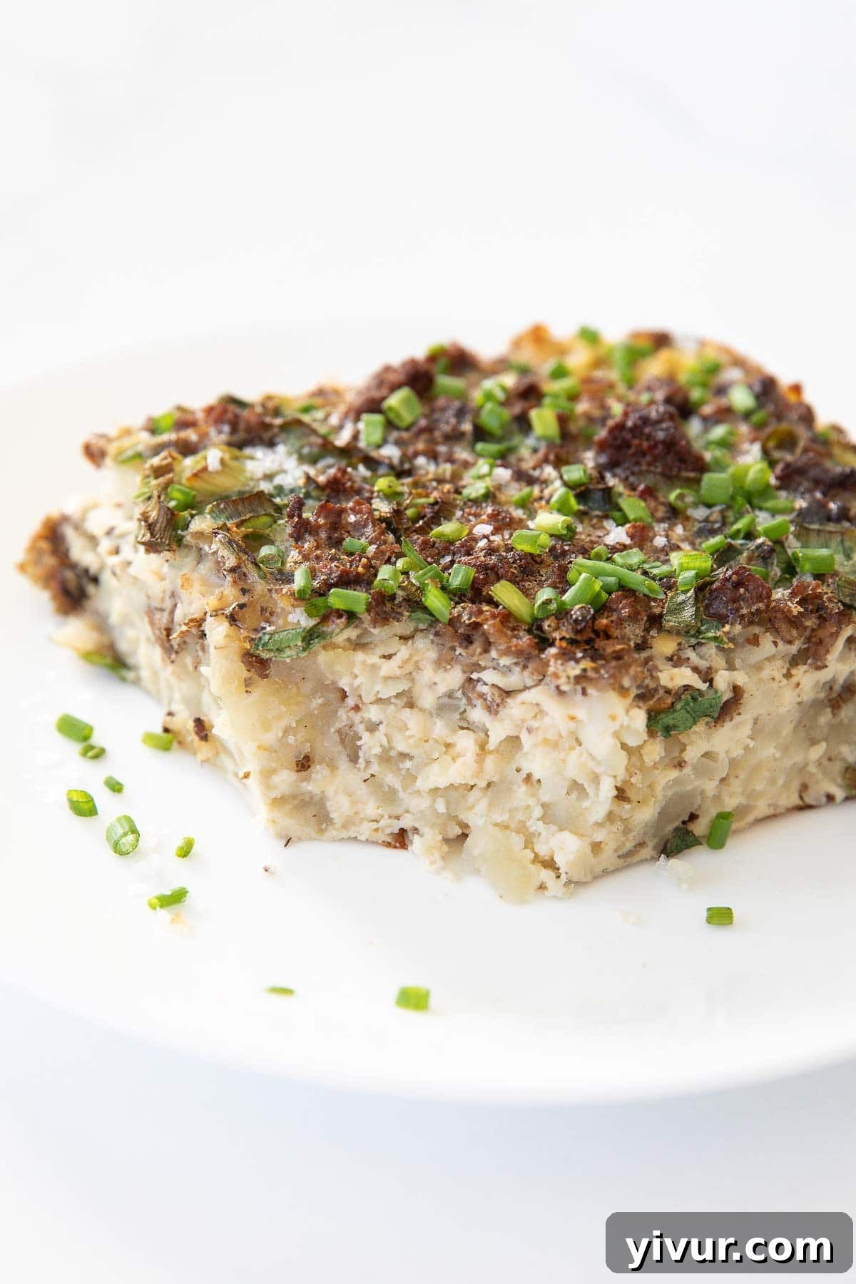 A delicious bite taken out of a High Protein Bison Breakfast Casserole with Potatoes and Eggs on a white plate