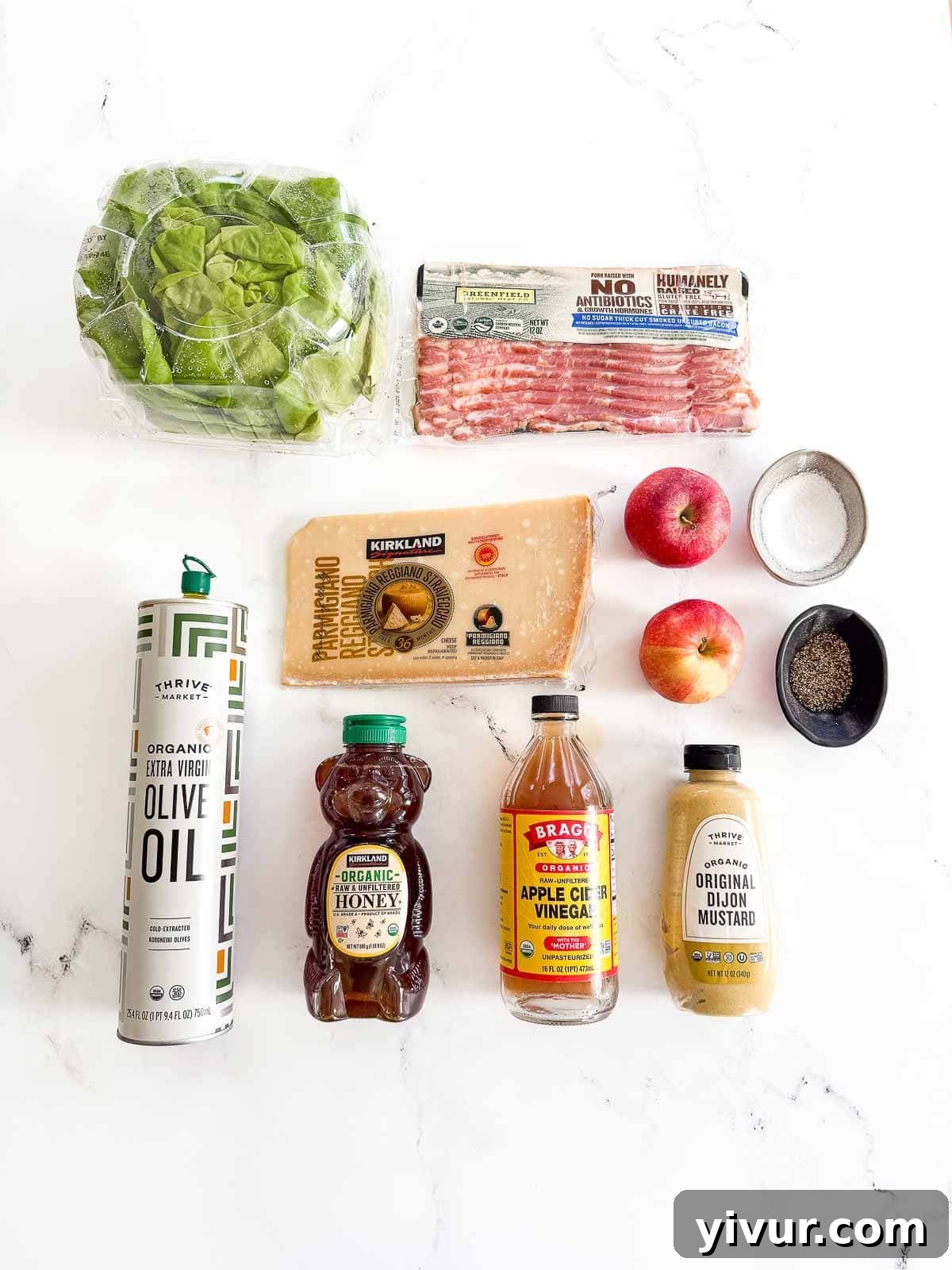 A flat lay image displaying all the fresh ingredients required to make the Butter Leaf Lettuce Salad with Bacon, Apple & Shaved Parmesan, including lettuce, bacon, apples, and cheese.